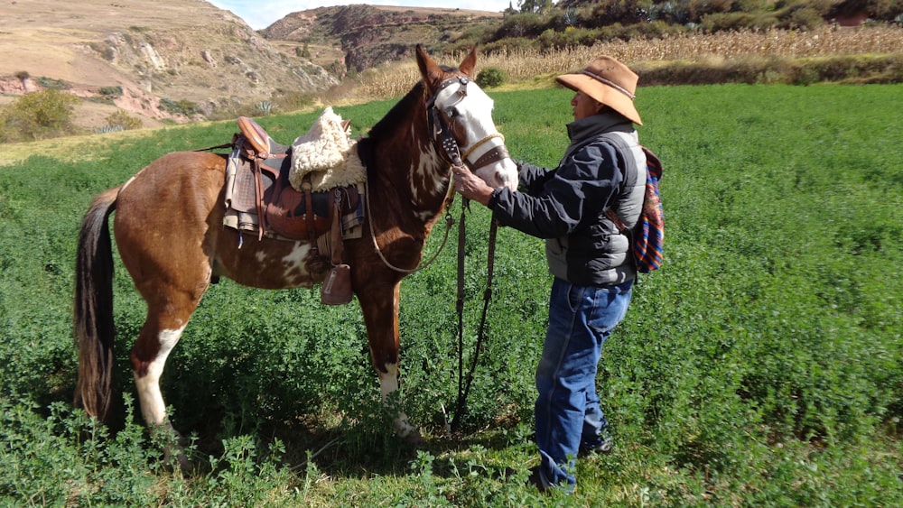 a man standing next to a horse in a field