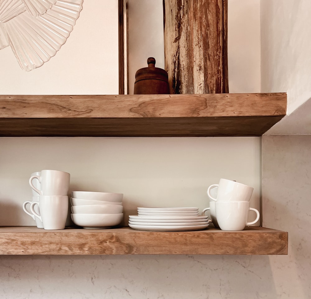 a shelf filled with white dishes and cups