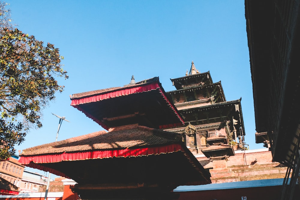 a tall building with a red roof next to a tree