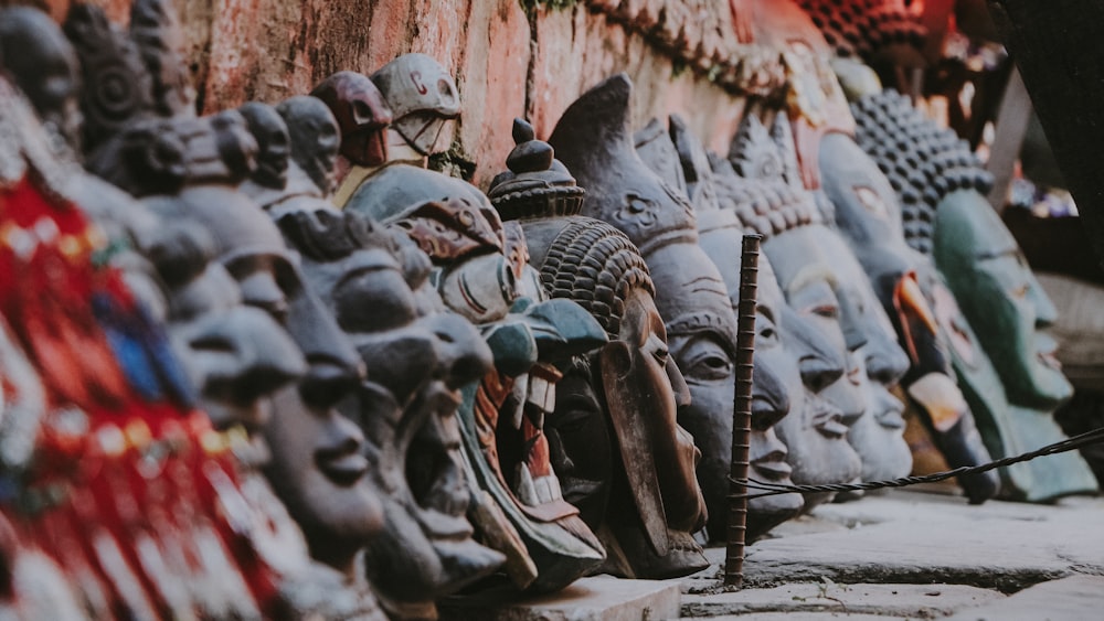 a row of masks sitting on top of a stone wall