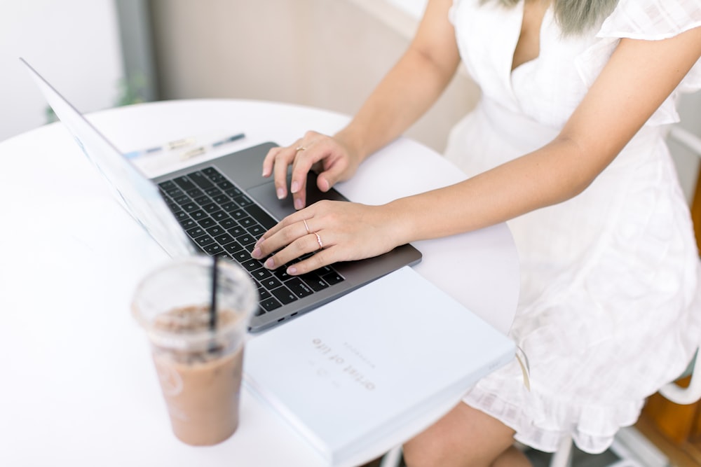 a woman sitting at a table using a laptop computer