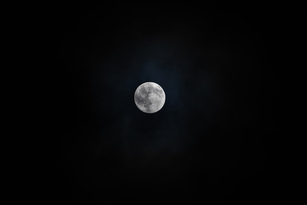 a full moon seen through the clouds in the night sky