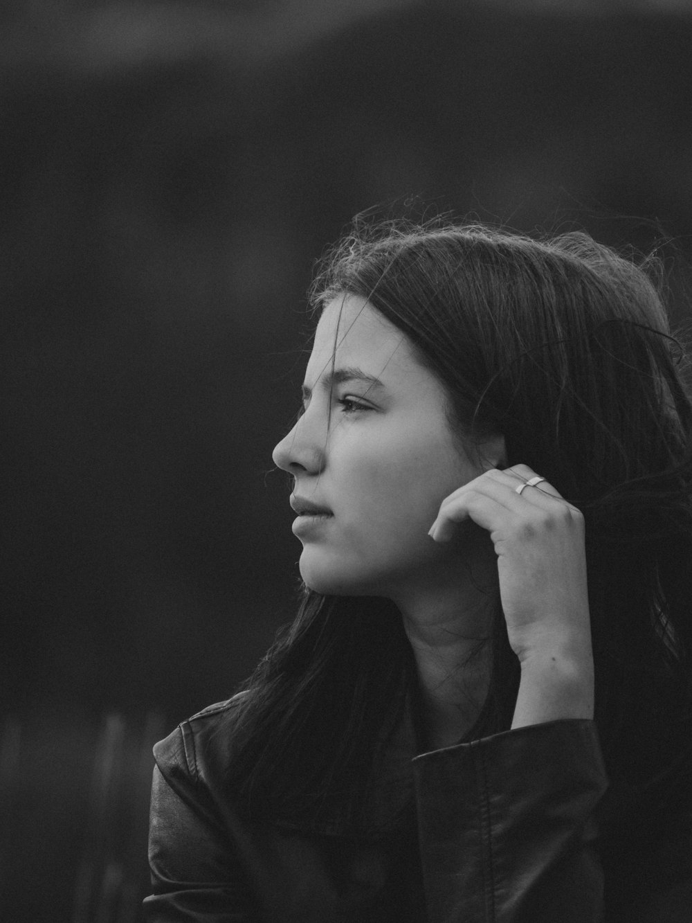 a black and white photo of a woman with her hair blowing in the wind