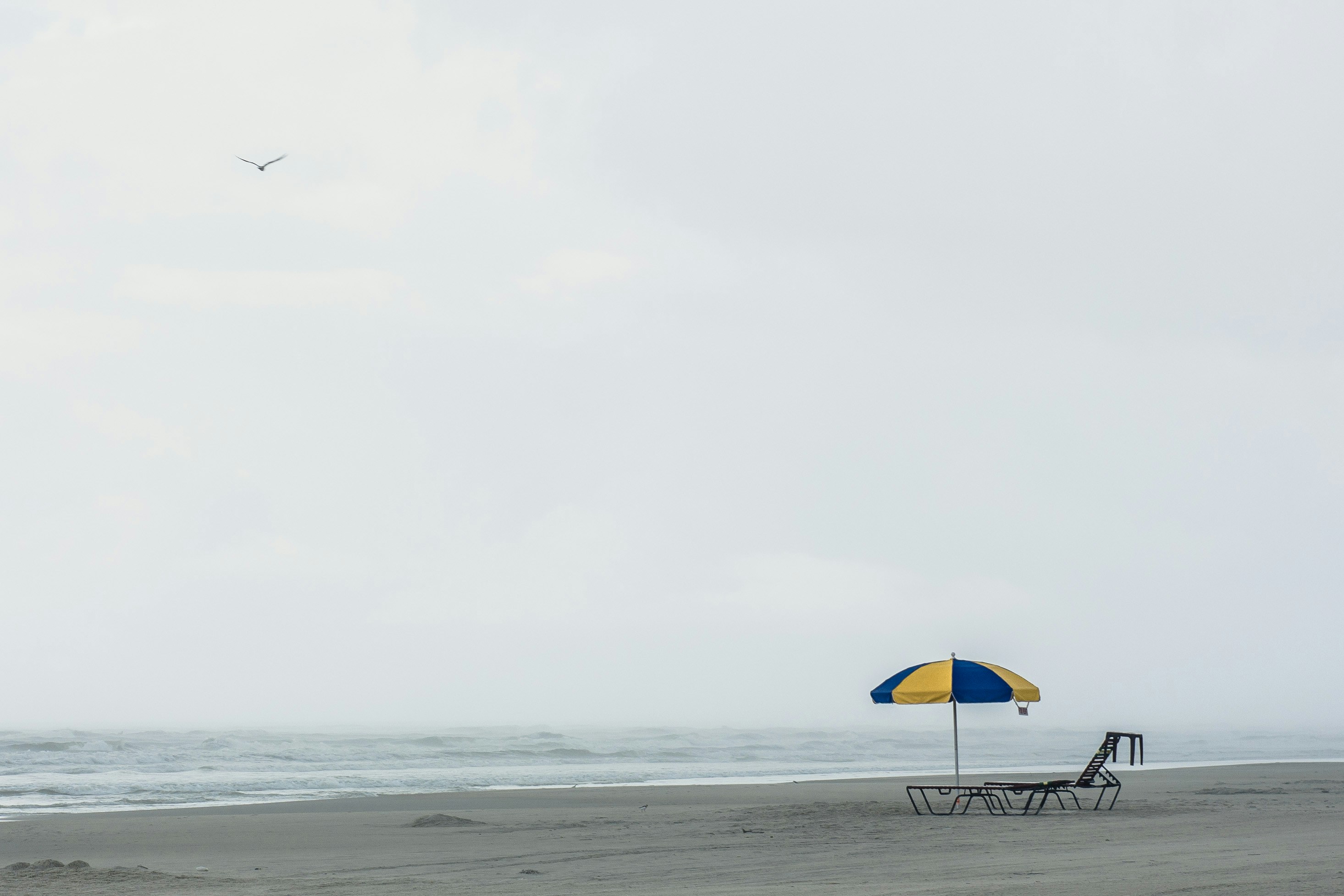 Small yellow and blue umbrella on a quiet grey beach