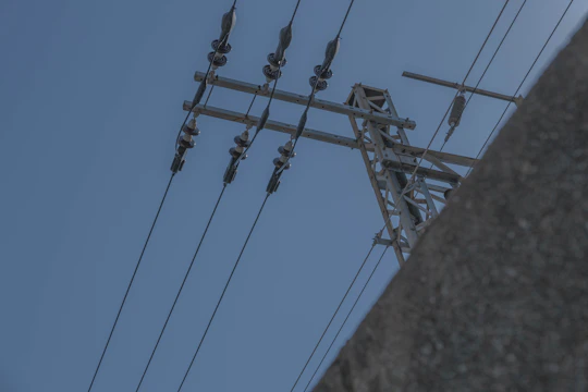 Close-up of a silicone polymer insulator installed on a high-voltage power line under a clear blue sky.