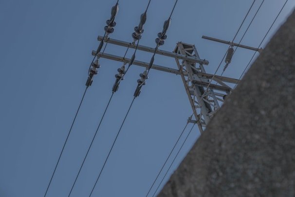Porcelain insulators installed on high-voltage power lines against a clear blue sky.