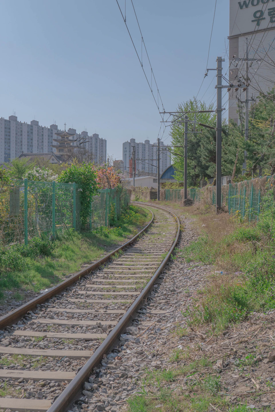 Wooden train tracks winding through lush landscape with trees and distant urban buildings
