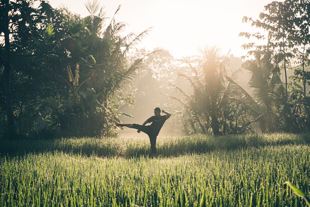 a person in a field doing a karate kick