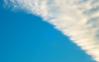 A clear blue sky transitions into soft, white clouds along one edge, creating a striking contrast between the vibrant blue and the pale hues of the clouds.