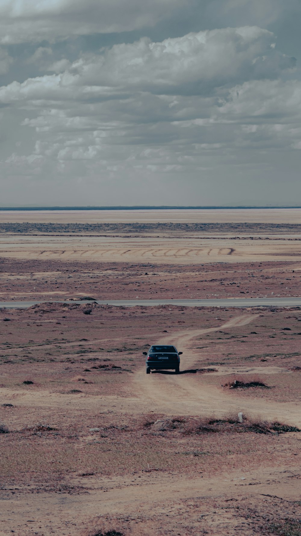 砂漠の真ん中にある未舗装の道路を運転する車