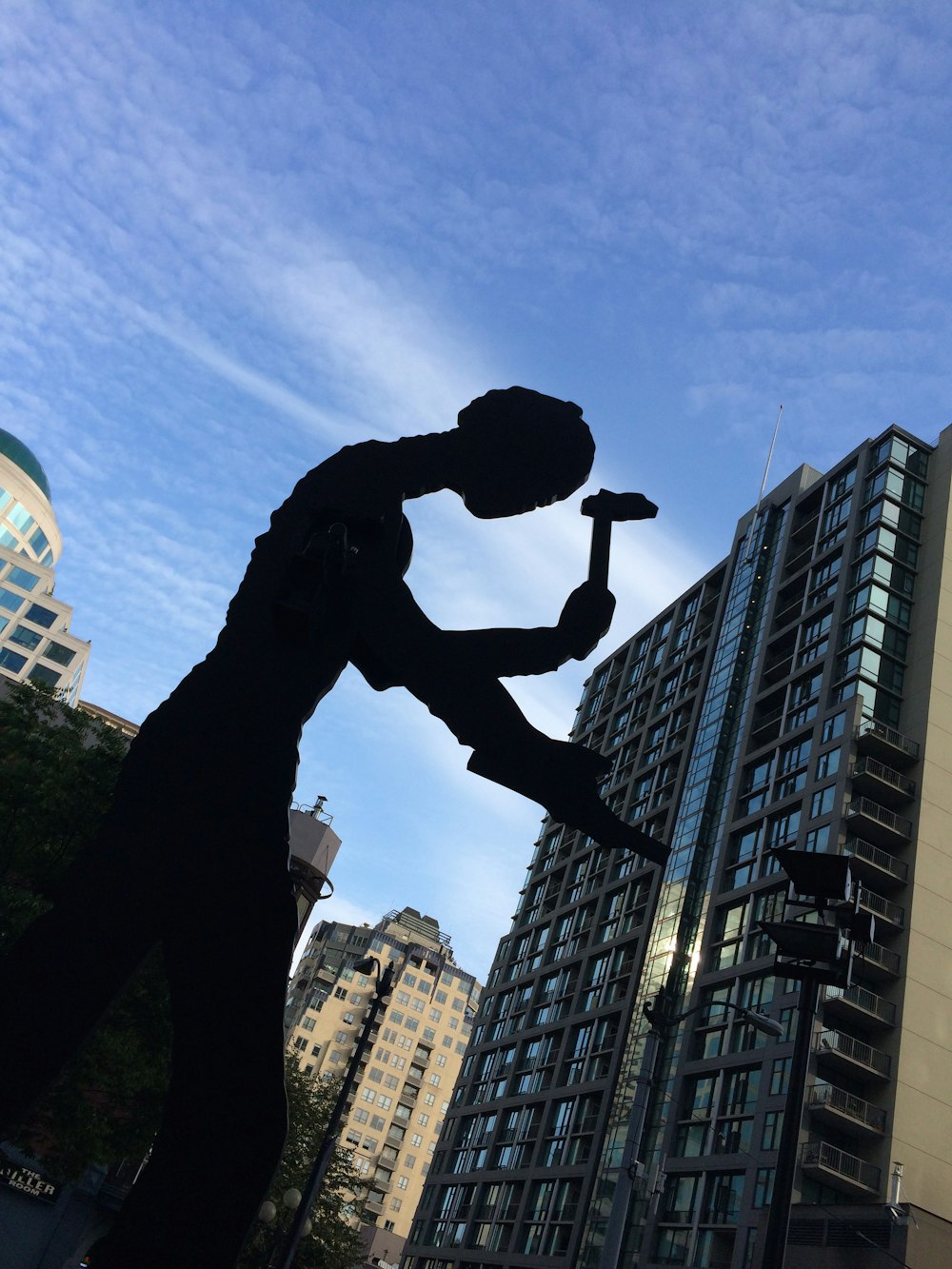 a statue of a man holding a hammer in front of a tall building