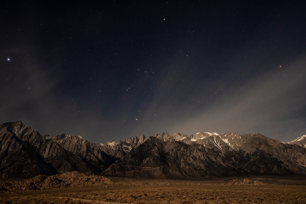 the night sky over a mountain range with stars in the sky