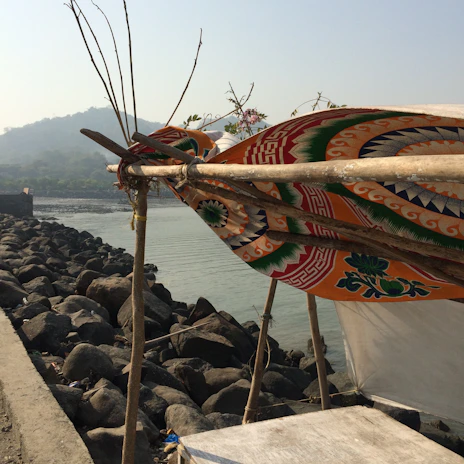 A colorful shibumi sail casting a playful shadow over a cozy beach setup near the shoreline.