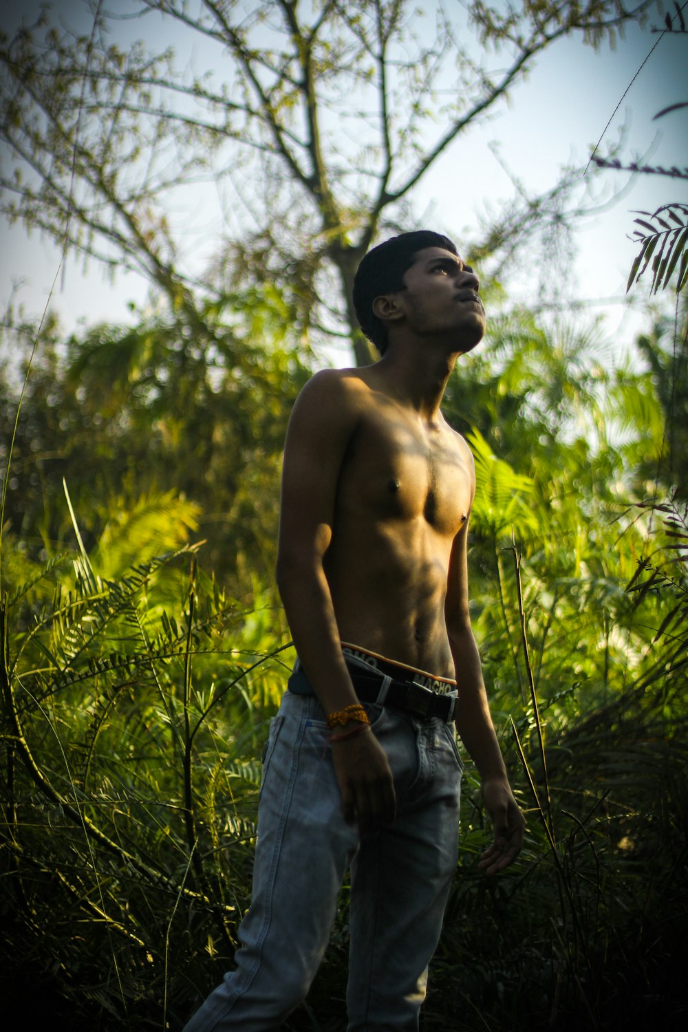 a man without a shirt standing in the grass