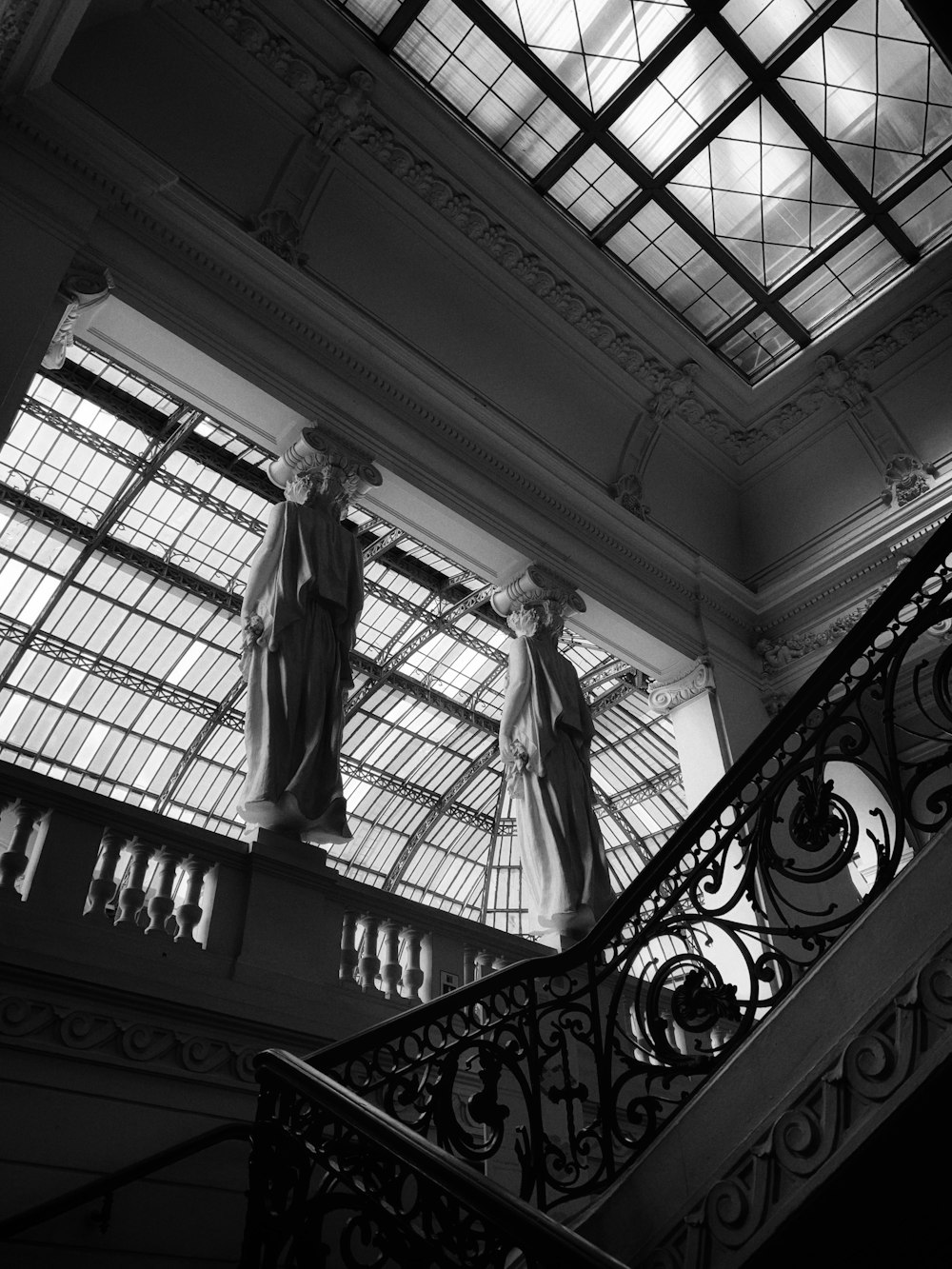 uma foto em preto e branco de duas estátuas em um edifício