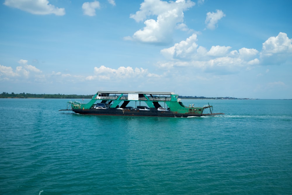 a green boat traveling across a large body of water