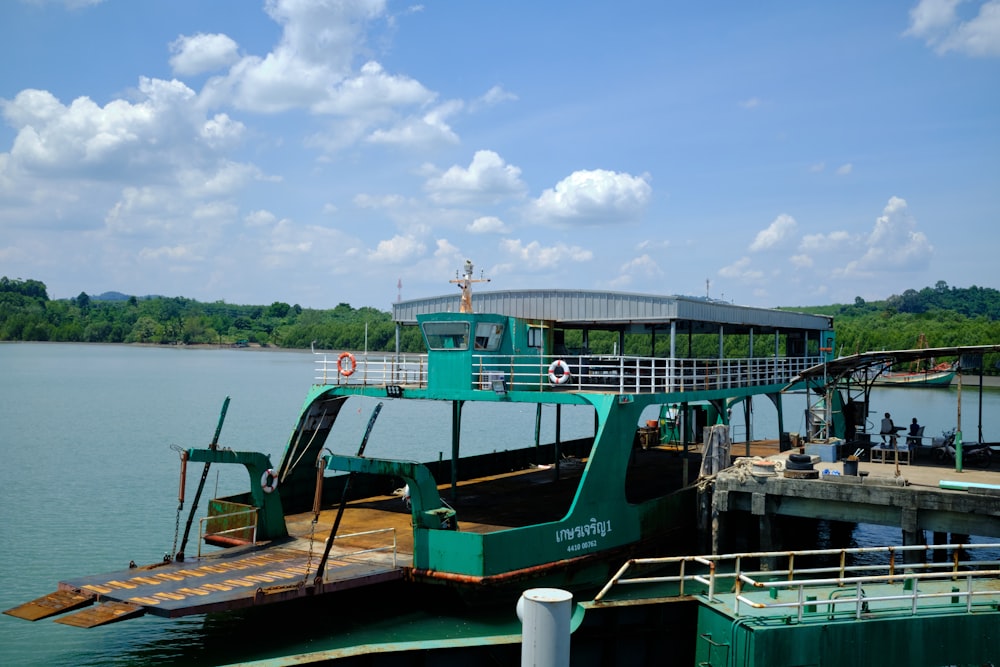 a green ferry boat docked at a pier