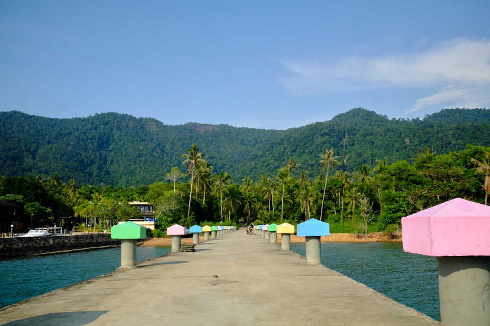 a long pier with a row of colorful umbrellas on top of it