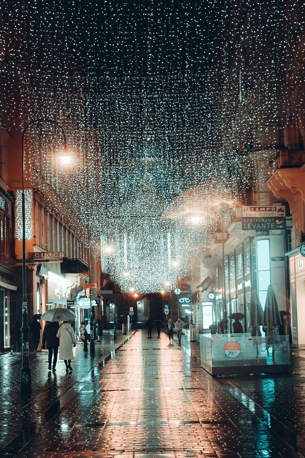 a couple of people walking down a rain soaked street