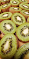 a bunch of kiwi cut in half on a cutting board