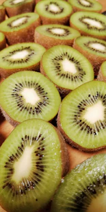 a bunch of kiwi cut in half on a cutting board
