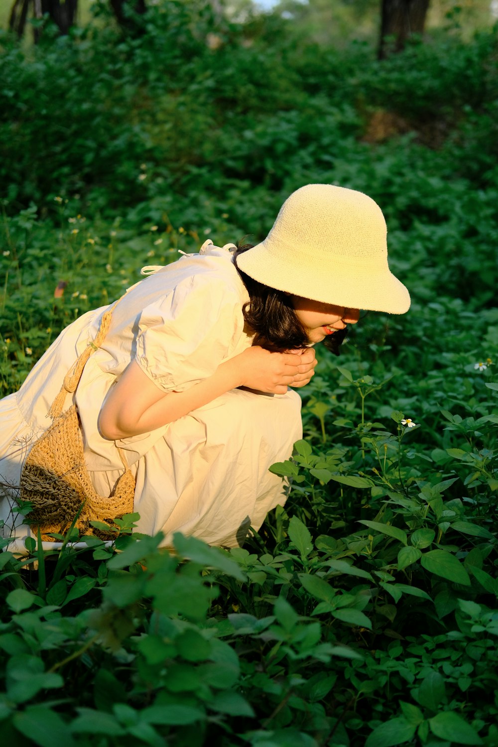 a woman kneeling in a field of green plants