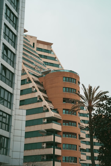a tall building with many windows next to a palm tree