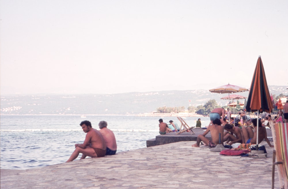 a group of people sitting on top of a beach next to the ocean