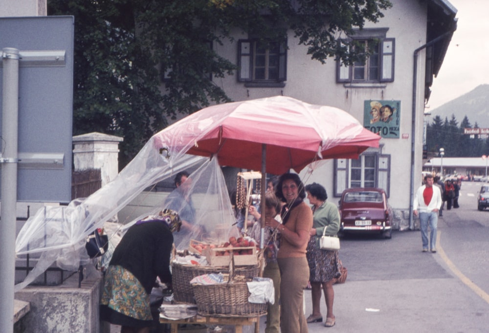 a group of people standing under a red umbrella