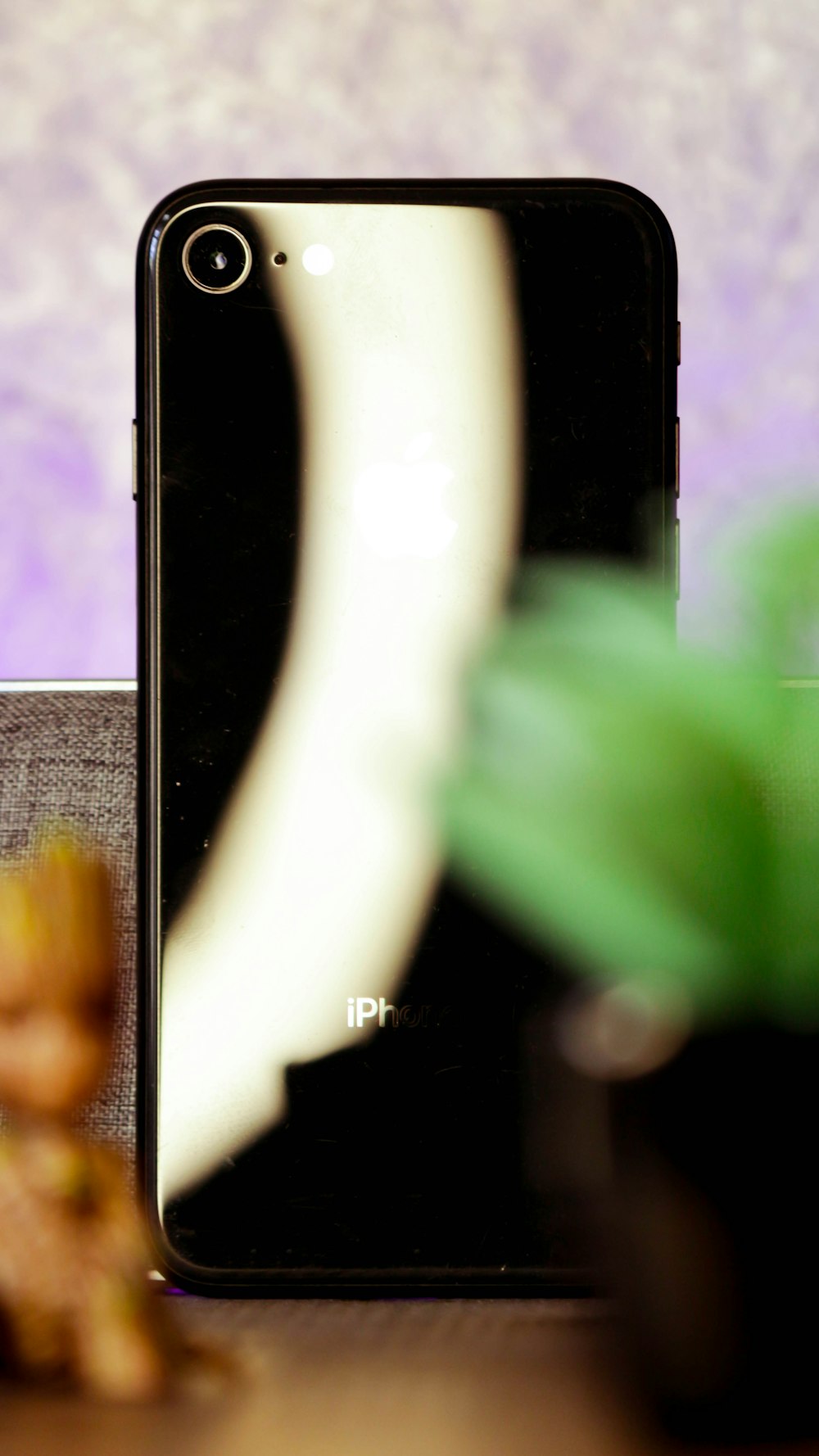 a cell phone sitting on top of a table next to a plant