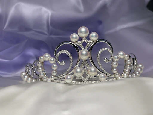 A delicate bridal tiara resting on soft white silk fabric, sparkling under gentle light.