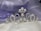 A luxurious silver tiara adorned with pearls and small diamonds rests on a soft, silky fabric backdrop in shades of lavender and white. The tiara features intricate scrollwork with a symmetrical design, combining elegance and regal sophistication.
