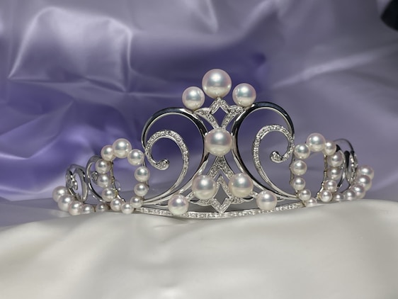 A delicate bridal tiara resting on soft white silk, catching the light with a gentle sparkle.