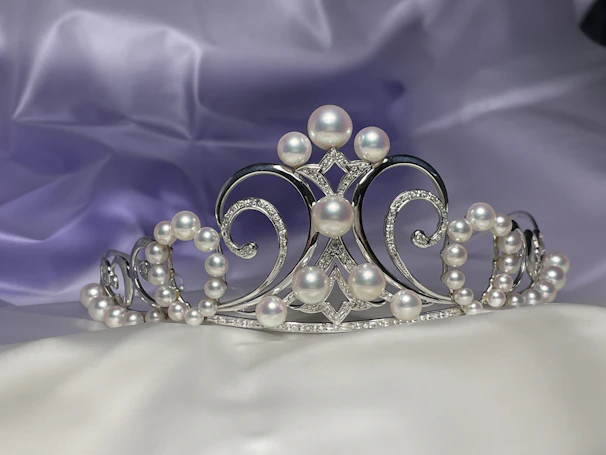 A delicate bridal tiara sparkling with crystals, resting on soft white silk fabric.