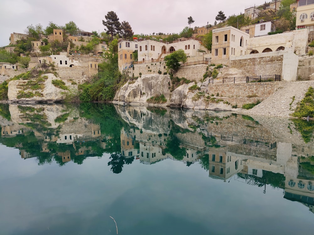 a body of water with buildings on a hill in the background