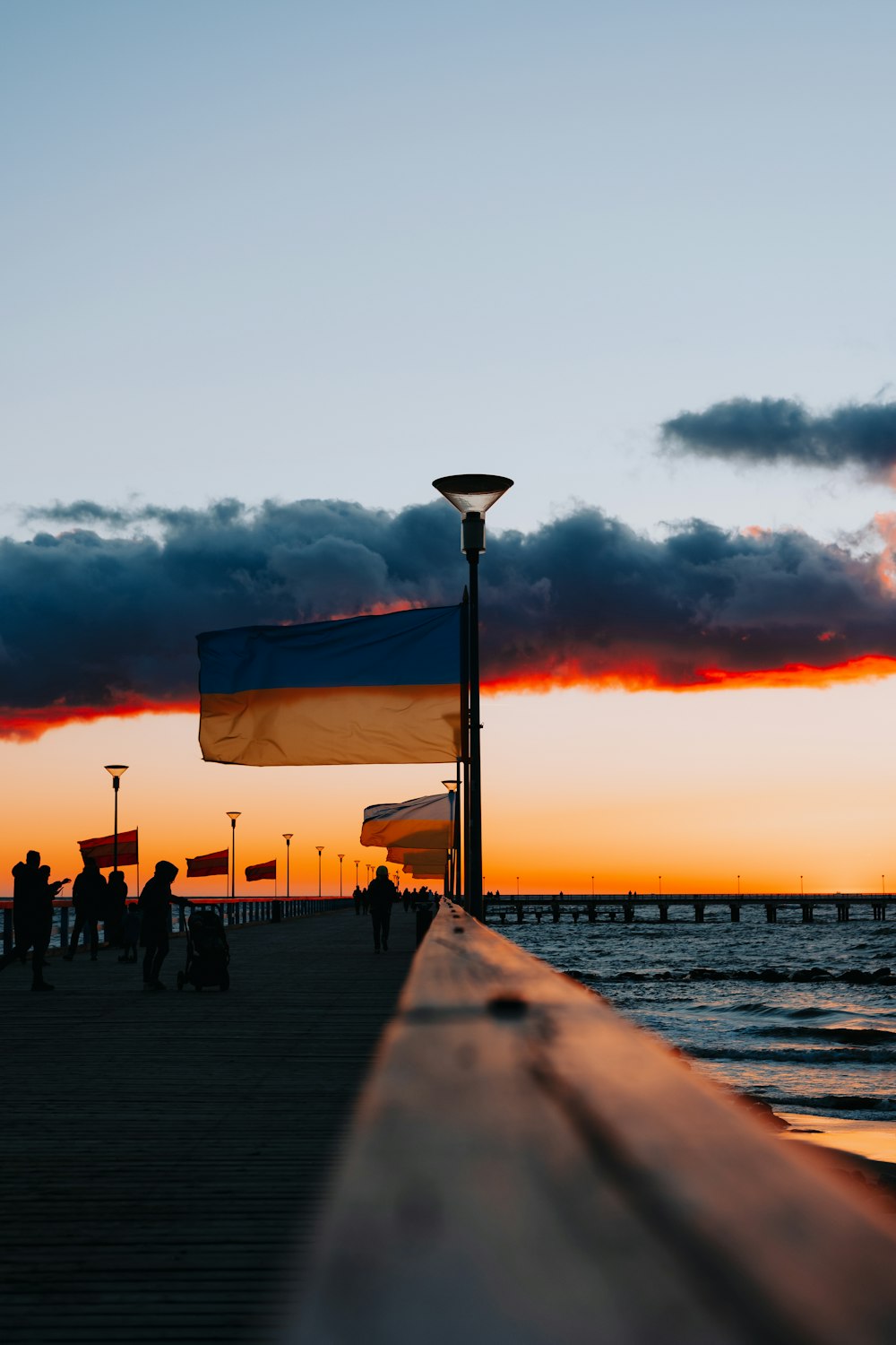 a pier with people walking on it at sunset