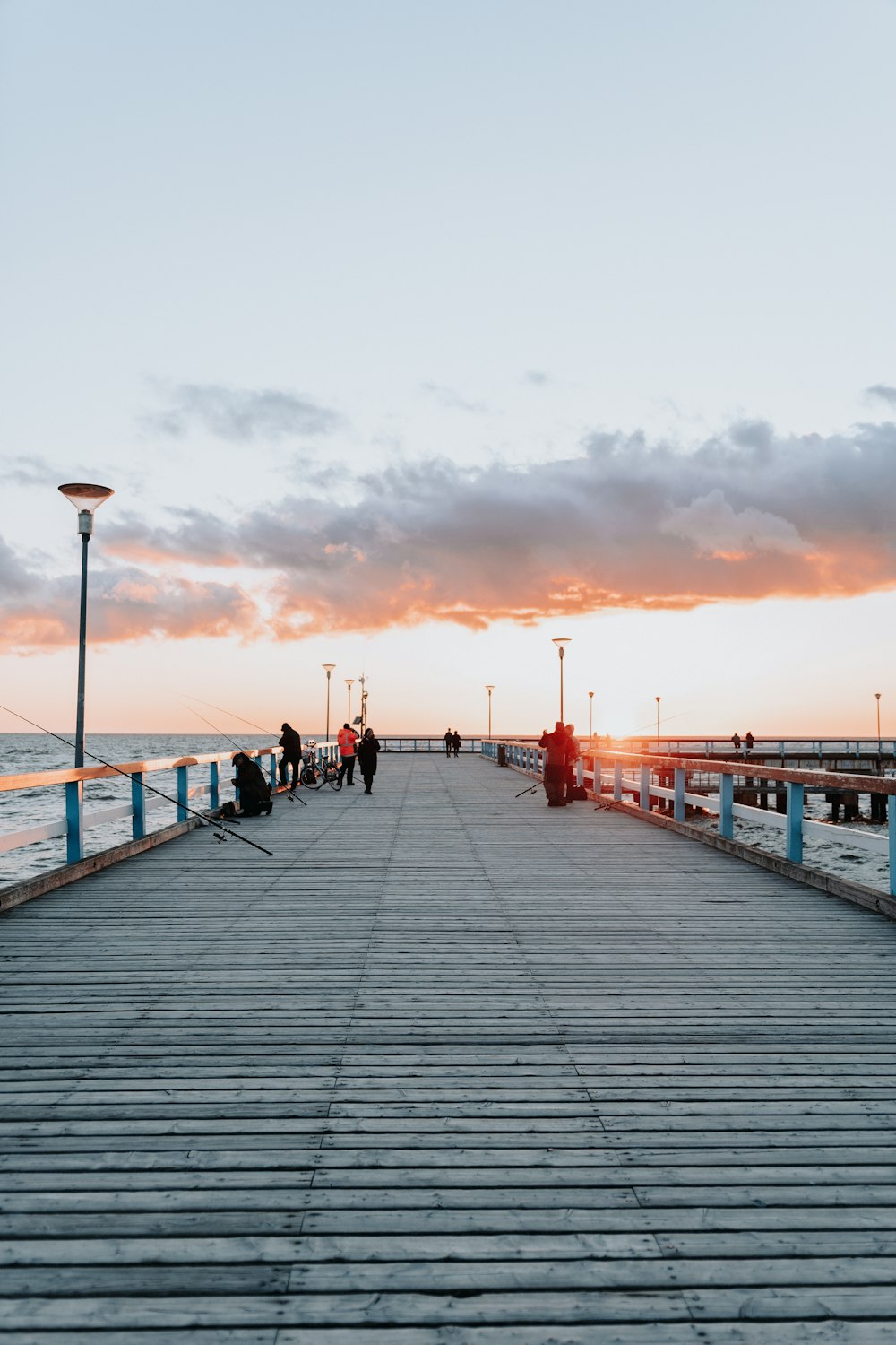 a pier with people walking on it at sunset