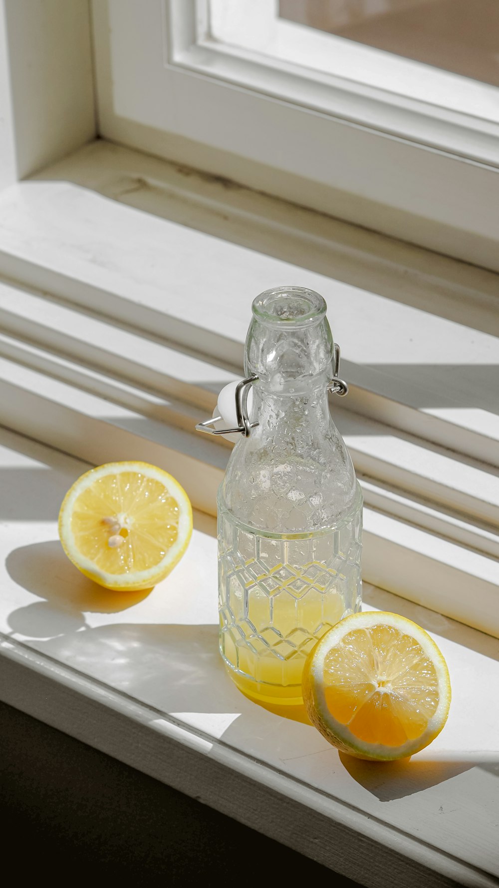 a bottle of lemon water sitting on a window sill
