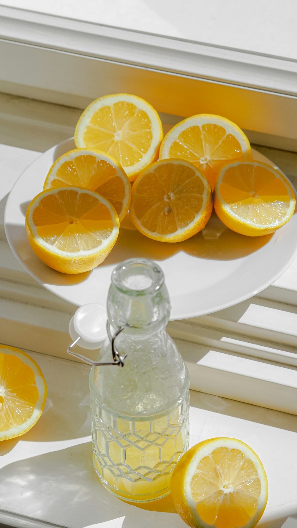 a plate of lemons and a bottle of water on a window sill