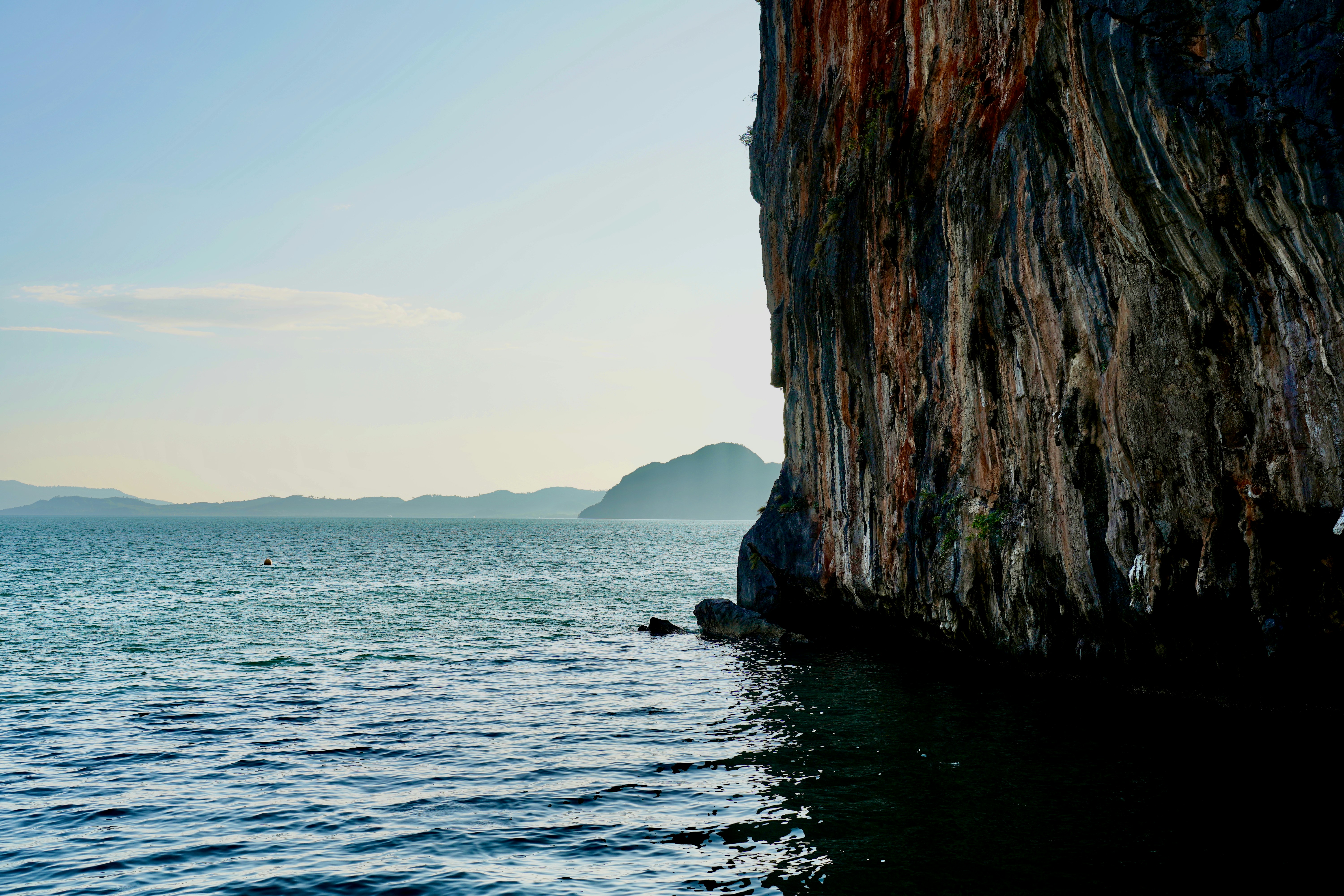a body of water next to a large cliff