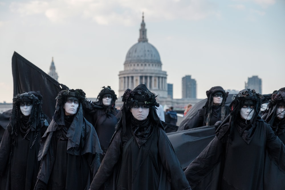 Foto Um grupo de pessoas vestidas de preto em pé na frente de um prédio –  Imagem de Cinza grátis no Unsplash