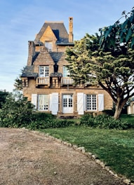 A charming older home in need of renovation, surrounded by mature trees.