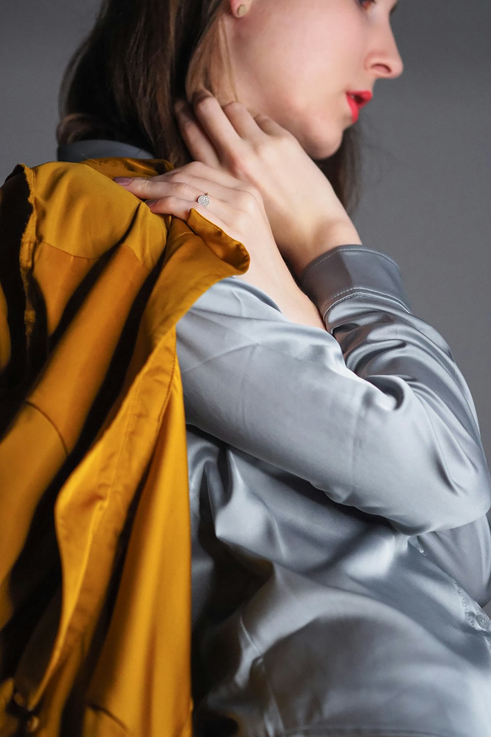 a woman is holding a yellow jacket over her shoulder