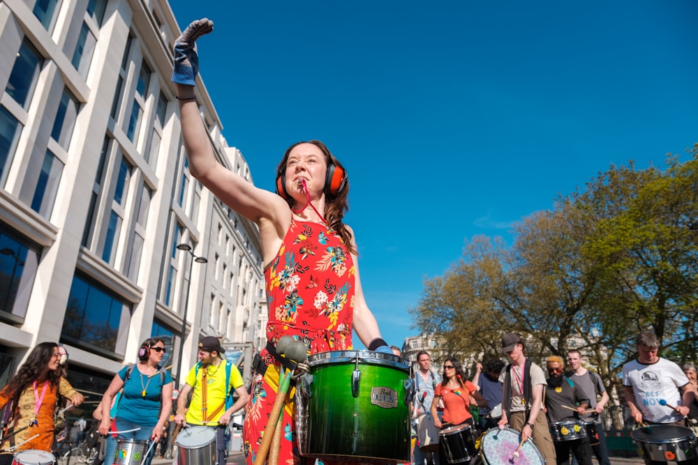 a woman in a colorful dress holding a green drum