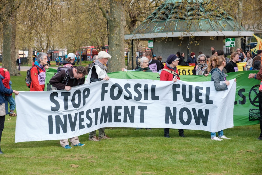 a group of people holding a sign that says stop fossil fuel investment now