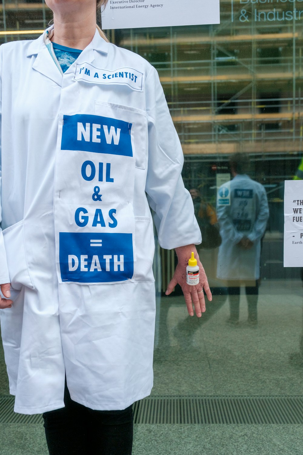 a woman in a white lab coat holding a bottle of oil