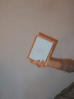Artist's hand gently placing a glass frame over a signed photographic print.