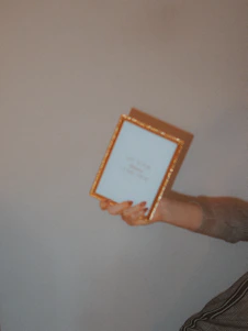 A close-up photo of hands carefully adjusting a framed picture beside a company logo on a wall.