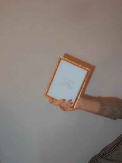 A close-up photo of hands carefully adjusting a framed picture beside a company logo on a wall.