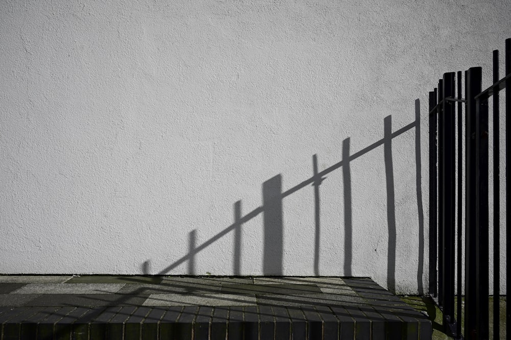 uma sombra de uma cerca em uma parede branca